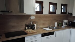 Een moderne keuken met witte kastjes, een houten aanrecht, een vaatwasser en een koffiezetapparaat.