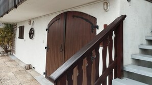 Een houten deur met een metalen handgreep, een witte muur en een houten trap.