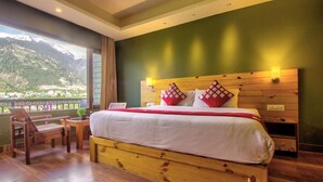 Ein Hotelzimmer mit einem großen Bett, einem Holzkopfstück und Blick auf Berge.
