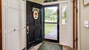 A black door with a 'WELCOME' sign, a doormat, and a view of a green lawn and trees. - Winnipesaukee waterfront escape with private dock and guest cottage (Tuftonboro)
