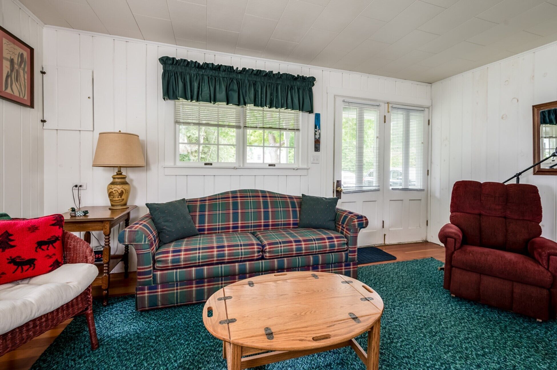 A living room with a plaid sofa, a red armchair, a wooden coffee table, and a green carpet.