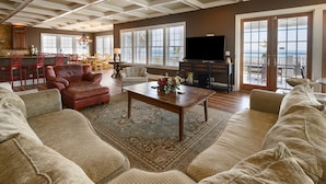 A spacious living room with a large sofa, a coffee table, and a fireplace. There is a dining area in the background with a table and chairs. - Oceanfront 8 BR Beach House with a Private Pool! Haven of Rest (Murrells Inlet)