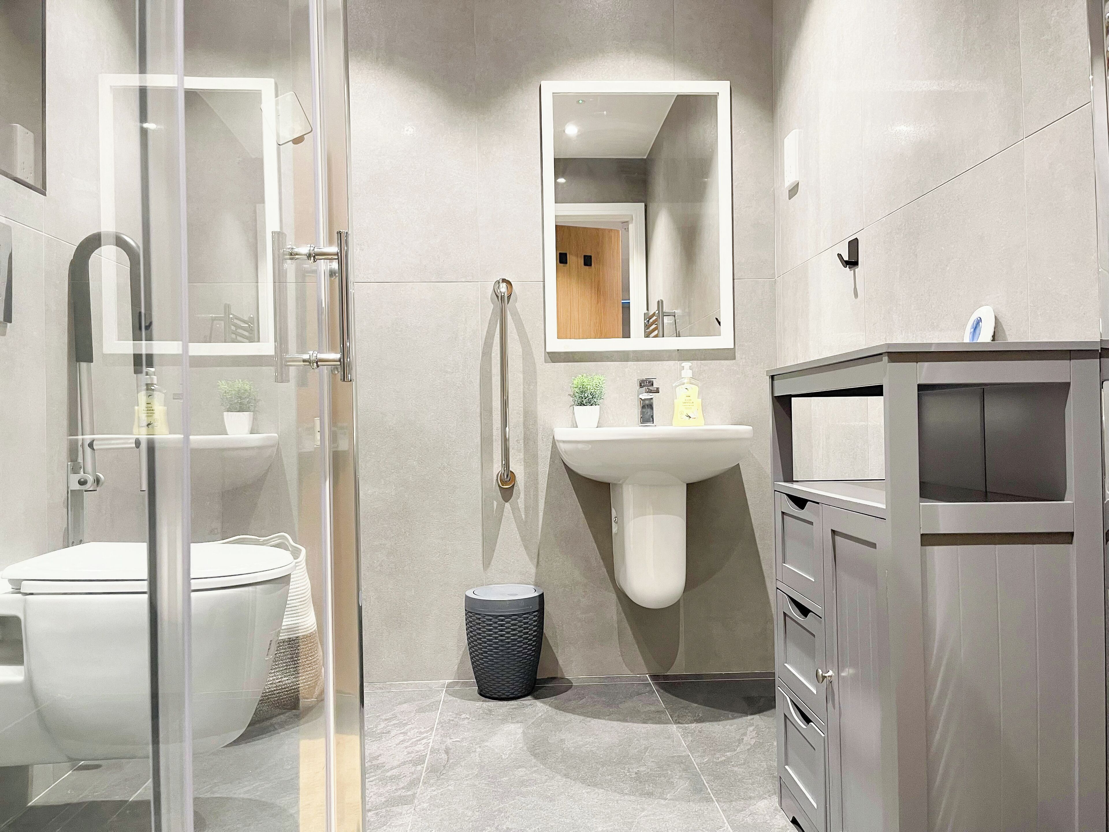 Une salle de bain moderne avec une douche à parois de verre, un lavabo sur colonne et un meuble-lavabo avec des tiroirs.