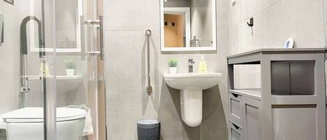Une salle de bain moderne avec une douche à parois de verre, un lavabo sur colonne et un meuble-lavabo avec des tiroirs.
