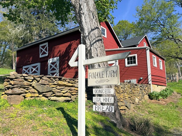 A red barn with a sign indicating it is a farm selling organic eggs, local honey, and bread.
