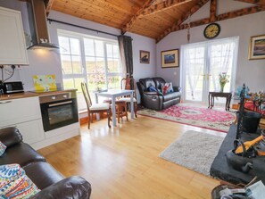 A cozy living room with a fireplace, a dining area, and a kitchen with wooden cabinets and a built-in oven.