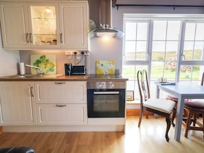 A kitchen with a built-in oven, a dining table with chairs, and a window with a view of the outdoors.