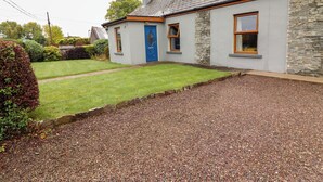 A house with a stone facade, a blue door, and a gravel driveway. - SUSIE'S COTTAGE, pet friendly in Beaufort, County Kerry (KILLARNEY)