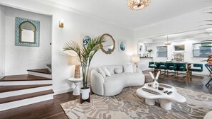 A modern living room with a white sofa, a coffee table, and a staircase. - NEW! Historic Estate-Heated Pool - Two Guest Houses - Sleep16 - NEAR EVERYTHING (West Palm Beach)