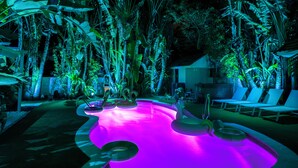 A pool area with a curved edge, surrounded by tropical plants and palm trees, and includes lounge chairs and a hot tub. - NEW! Historic Estate-Heated Pool - Two Guest Houses - Sleep16 - NEAR EVERYTHING (West Palm Beach)