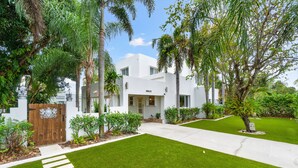 A modern house with a well-maintained lawn, a wooden gate, and a clear sky. - NEW! Historic Estate-Heated Pool - Two Guest Houses - Sleep16 - NEAR EVERYTHING (West Palm Beach)