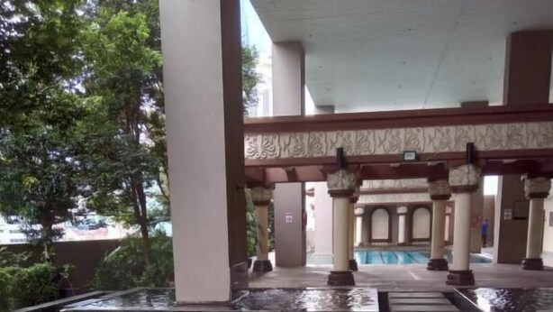A swimming pool with a tiled deck and a covered area with columns. - Maytower Service Studio Apartment (Kuala Lumpur)