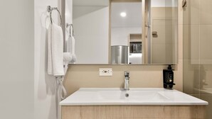 A modern bathroom with a white sink, wooden vanity, and a mirror.