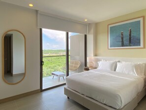 A bedroom with a large bed, a chair, a nightstand, a painting, and a view of greenery through a sliding door. - w Prestigious 2BR w Amazing View in Cartagena (Cartagena)