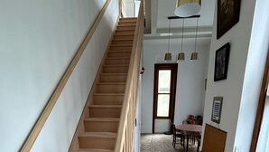 A staircase with wooden handrails leading to a landing. The landing has patterned flooring and a door leading to another room. - Small duplex "pointe du moulinet" in a listed villa (Dinard)