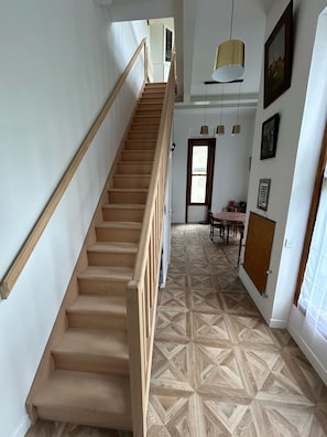 Stunning interior with a grand staircase, geometric patterned floor, and artwork-adorned walls.