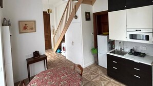 A modern kitchen with a built-in oven, a sink, and a dining area with a round table and chairs. - Small duplex "pointe du moulinet" in a listed villa (Dinard)