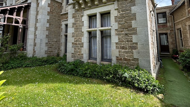 A historic stone building with a symmetrical facade, large windows, and a well-maintained lawn. - Small duplex "pointe du moulinet" in a listed villa (Dinard)