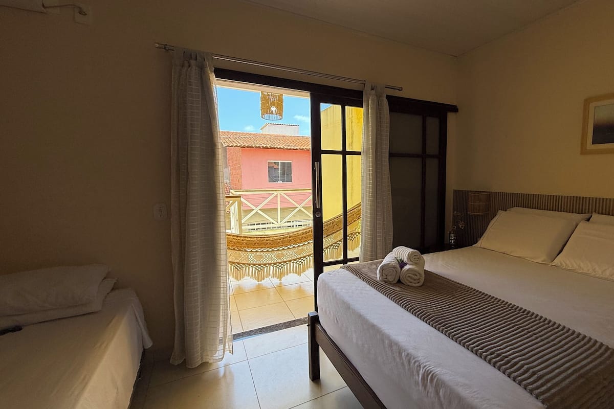 Ein Hotelzimmer mit Bett, einem Vorhangfenster, einem Bild an der Wand und Blick auf ein Gebäude.