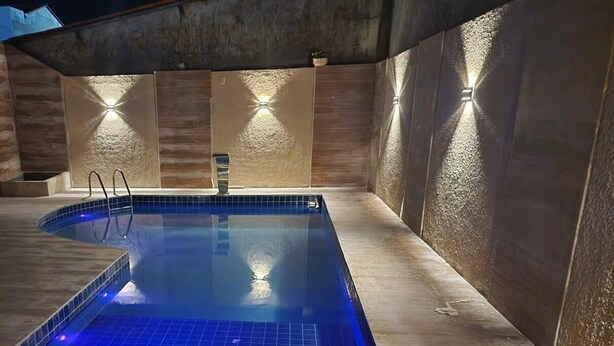 A swimming pool with a tiled floor and a wooden deck surrounding it. - POUSADA O PORTUGA (São Miguel dos Milagres)