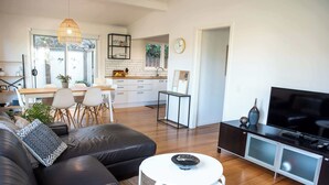 Ein modernes Wohnzimmer mit einer Couch, einem Essbereich, einer Küche und einem Fernseher.
