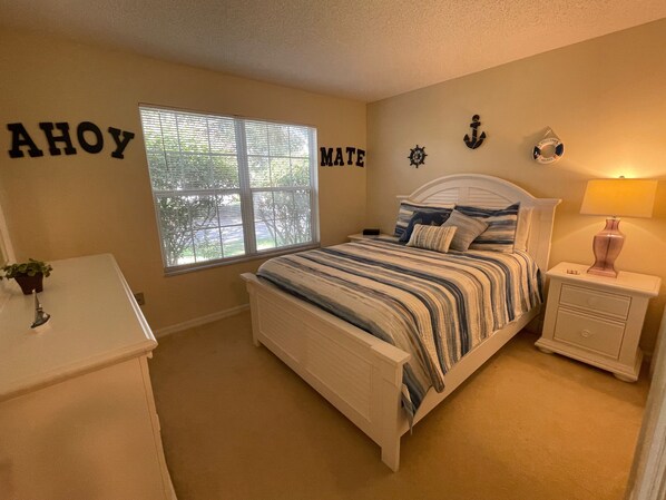 A bedroom with a bed, a nightstand, a dresser, a window, and wall decorations including letters and nautical symbols. - CALL TODAY FOR SPECIAL 2024/2025 RATES! Charming Retreat w/Golf Cart! (The Villages)