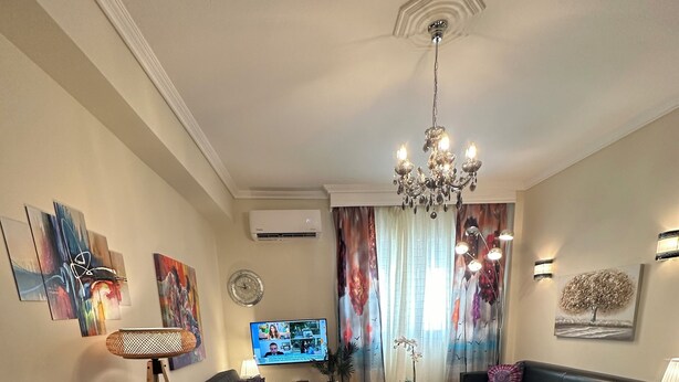 A modern living room with a dining table, chairs, a sofa, a chandelier, and artwork on the walls. - Allatini Sea View, Deluxe 2 Bedroom & Bathroom Apartment in Thessaloniki (Thessaloniki)