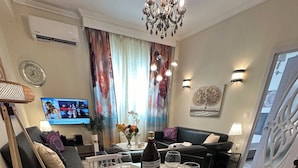 A dining area with a round table set for six, surrounded by chairs. A bottle of wine is placed on the table. - Allatini Sea View, Deluxe 2 Bedroom & Bathroom Apartment in Thessaloniki (Thessaloniki)