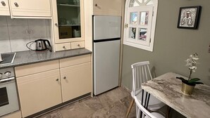 A kitchen with beige cabinets, a refrigerator, a stove, and a dining area with a table and chairs. - Allatini Sea View, Deluxe 2 Bedroom & Bathroom Apartment in Thessaloniki (Thessaloniki)