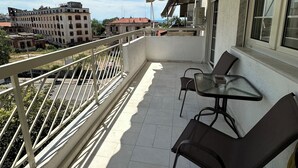A balcony with a table and chairs, a view of a building across the street, and a railing. - Allatini Sea View, Deluxe 2 Bedroom & Bathroom Apartment in Thessaloniki (Thessaloniki)
