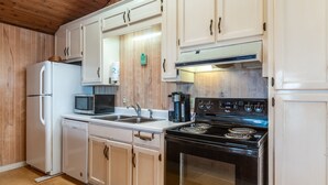 A compact kitchen with white cabinets, a black stove, a microwave, and a dishwasher. - Happy Lee Ever After - 1424 Cadillac Avenue 2 Bedroom Home (Dauphin Island)