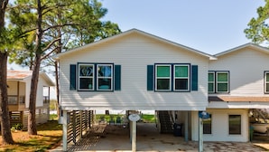 A two-story house with a covered porch and a small deck area. - Happy Lee Ever After - 1424 Cadillac Avenue 2 Bedroom Home (Dauphin Island)