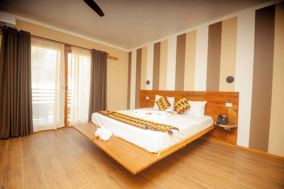 A hotel room with a bed, curtains, a telephone, and a wall-mounted light fixture.