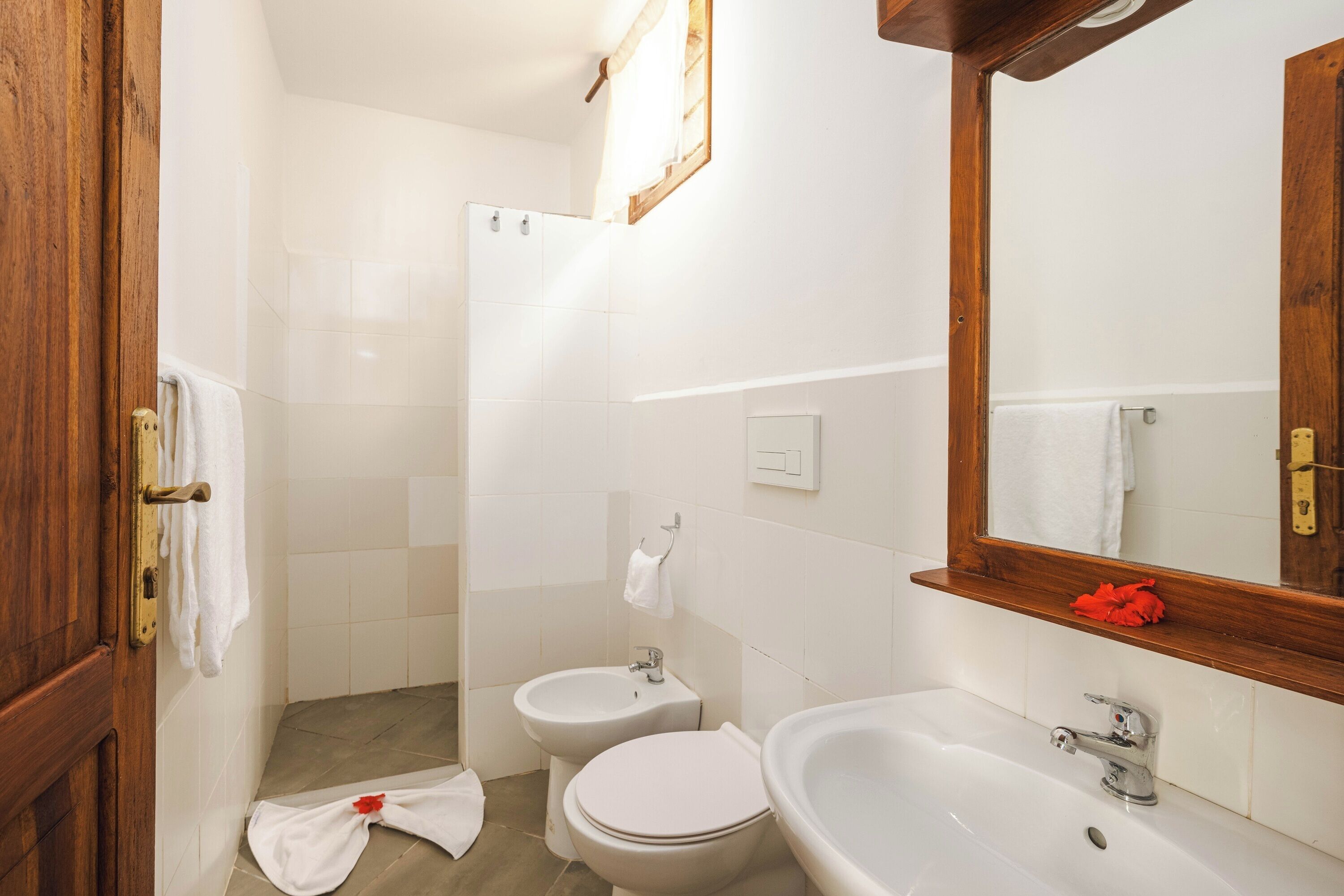 Un baño con inodoro, bidé, lavabo y espejo.