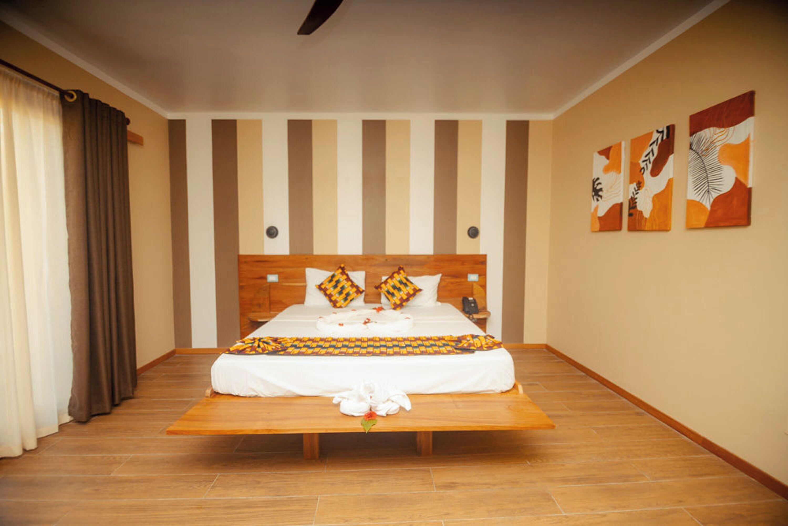A hotel room with a large bed, a wooden headboard, a bedside table, and a nightstand.