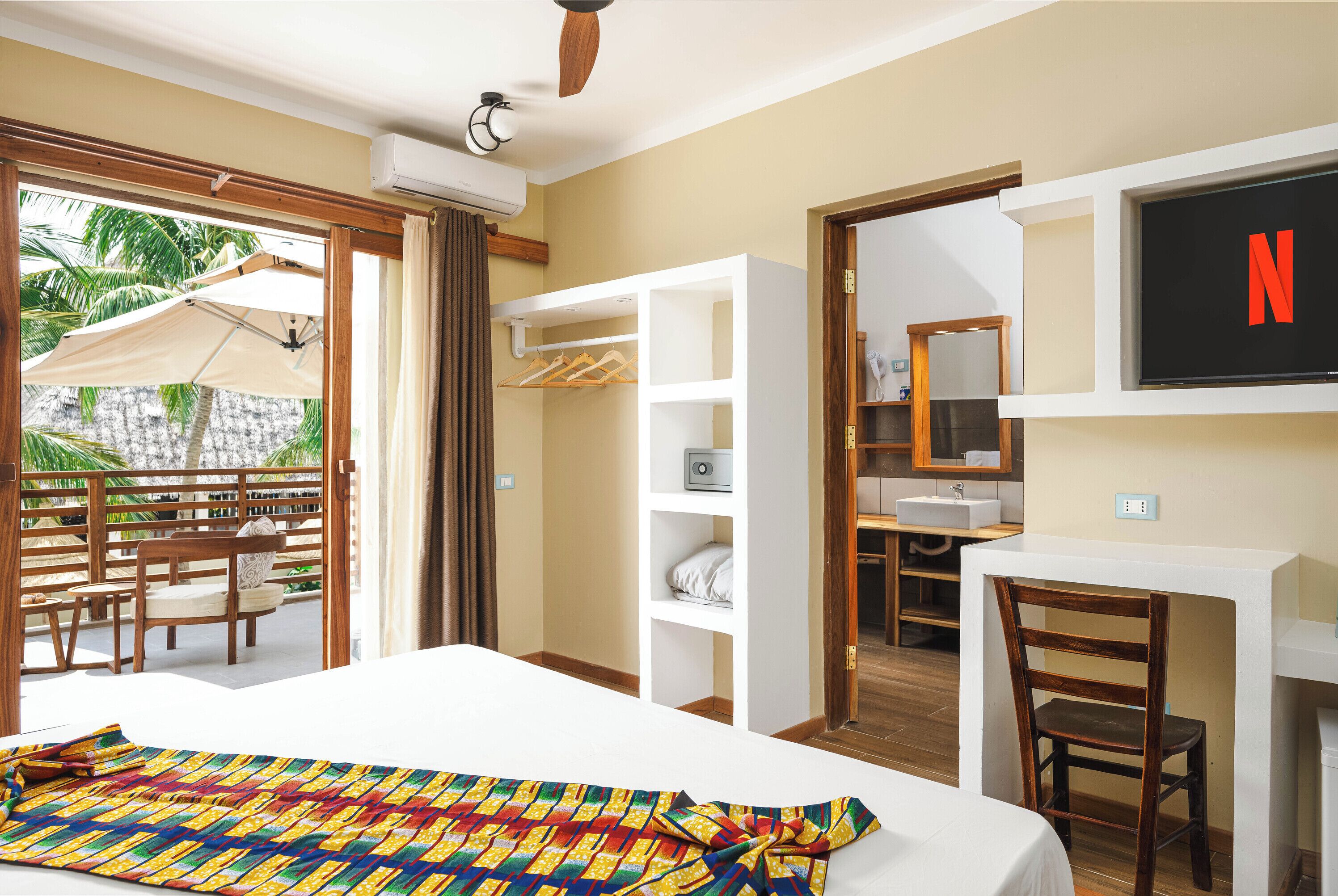 Una habitación de hotel con una cama, un escritorio, una silla, un armario y un televisor.