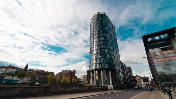 A modern curved building with a glass facade, located beside a road with a pedestrian walkway. - 2nd Floor City Apartment (Sheffield)