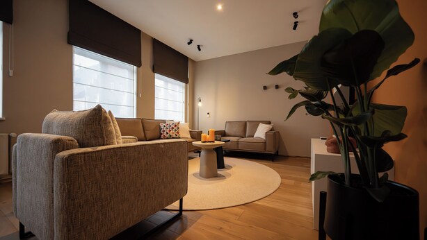Ein modernes Wohnzimmer mit einer Couch, einem Sessel und einem Couchtisch.