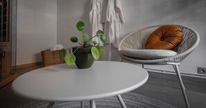 Relax in a serene space with a round table, potted plant, and comfortable wicker chair.