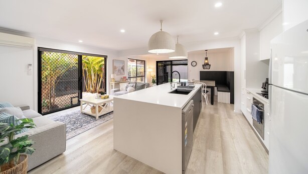 A modern kitchen with a central island, built-in appliances, and a dining area with a sofa and coffee table.