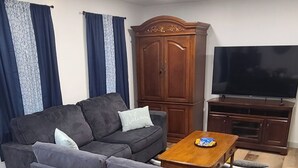 Una sala de estar moderna con un sofá gris, una mesa de centro de madera y un televisor de pantalla plana.