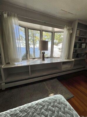 A room with a large window, a built-in bench, a lamp, and a bookshelf. - WATERFRONT 5 BEDROOMS AND 2 BATHROOMS (Sebago)