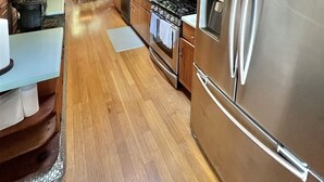 Une cuisine rustique aménagée dans une cabane en bois, avec un réfrigérateur, une cuisinière et un four à micro-ondes en acier inoxydable.