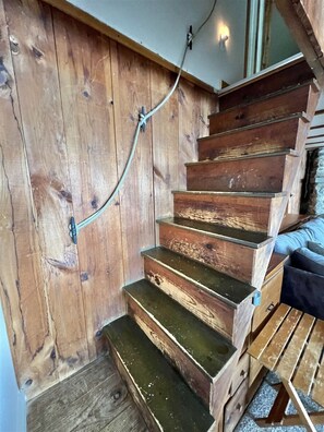 A wooden staircase with a metal handrail, leading to a room with a bed and a window. - WATERFRONT 5 BEDROOMS AND 2 BATHROOMS (Sebago)