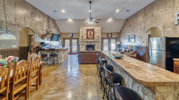 A spacious kitchen with a large island, stone walls, and a mounted deer head. - Large spacious home with wheelchair accessible pool (Concan)