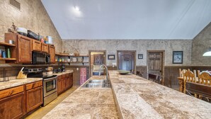 A spacious kitchen with wooden cabinets, a stainless steel stove, and a granite countertop. - Large spacious home with wheelchair accessible pool (Concan)