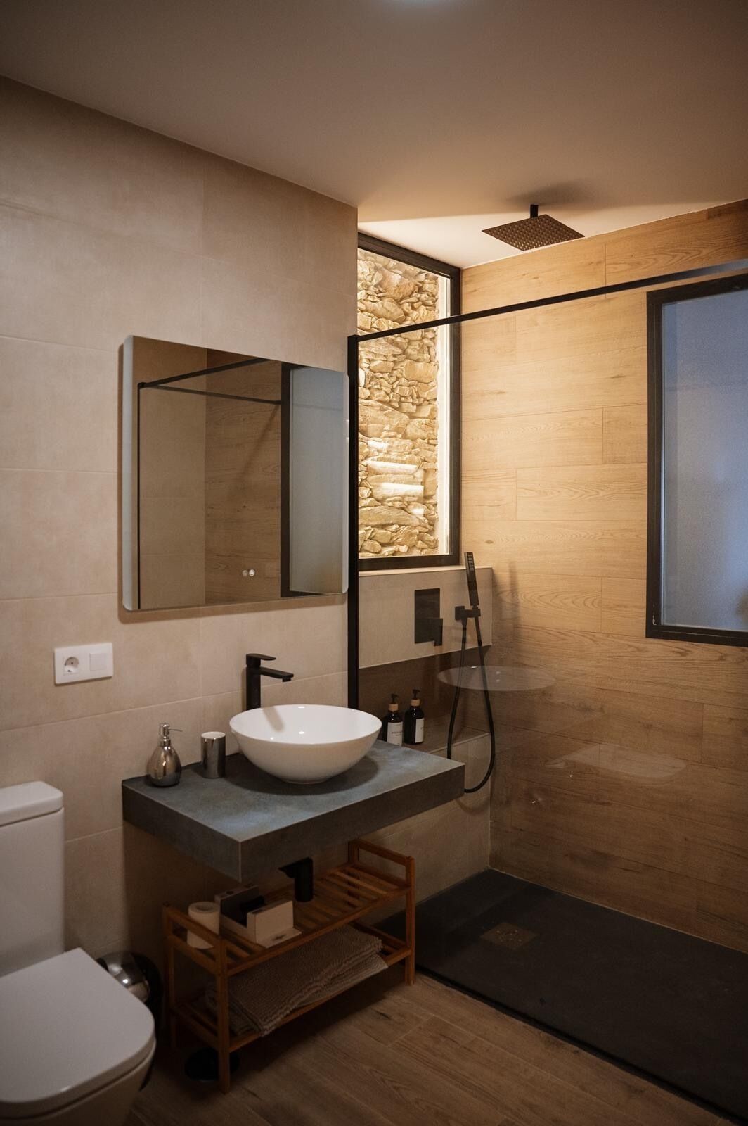 Ein modernes Badezimmer mit großem Spiegel, weißem Waschbecken und Dusche.