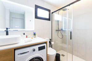Ein modernes Badezimmer mit Waschmaschine, Toilette und einer Duschkabine.