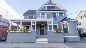 A two-story house with a front porch, a covered entryway, and a small circular window on the right side.