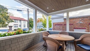 A covered outdoor patio with wicker furniture and a brick wall backdrop.